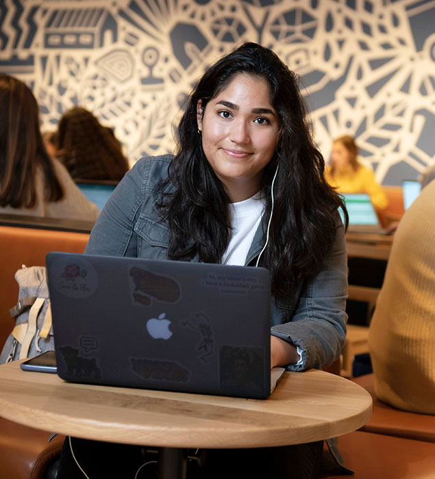 Student sitting at a table with a laptop at Starbucks in the Olmsted Center.